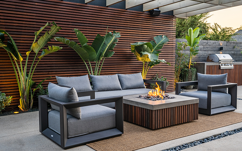 fire pit with loung seating around it and banana plants behind
