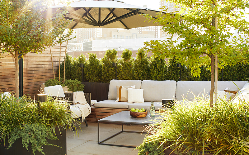 outdoor room on rooftop with hedge umbrella, couch, and containers