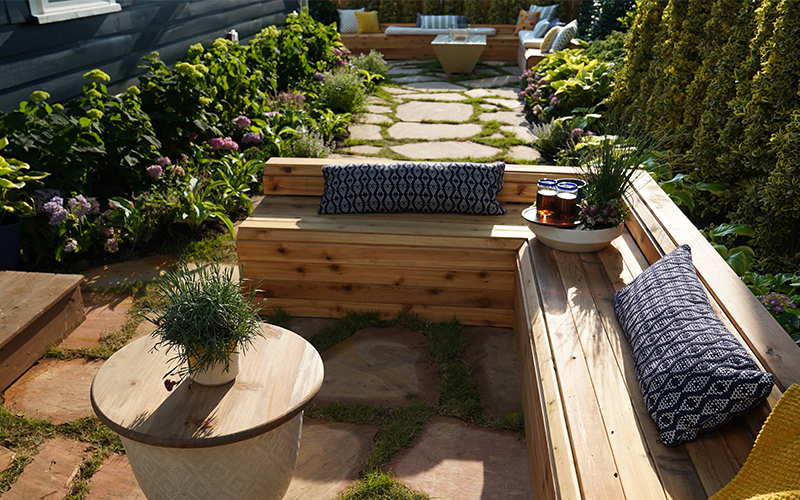 outdoor seating area with benches and plants including canadian hemlock and hostas