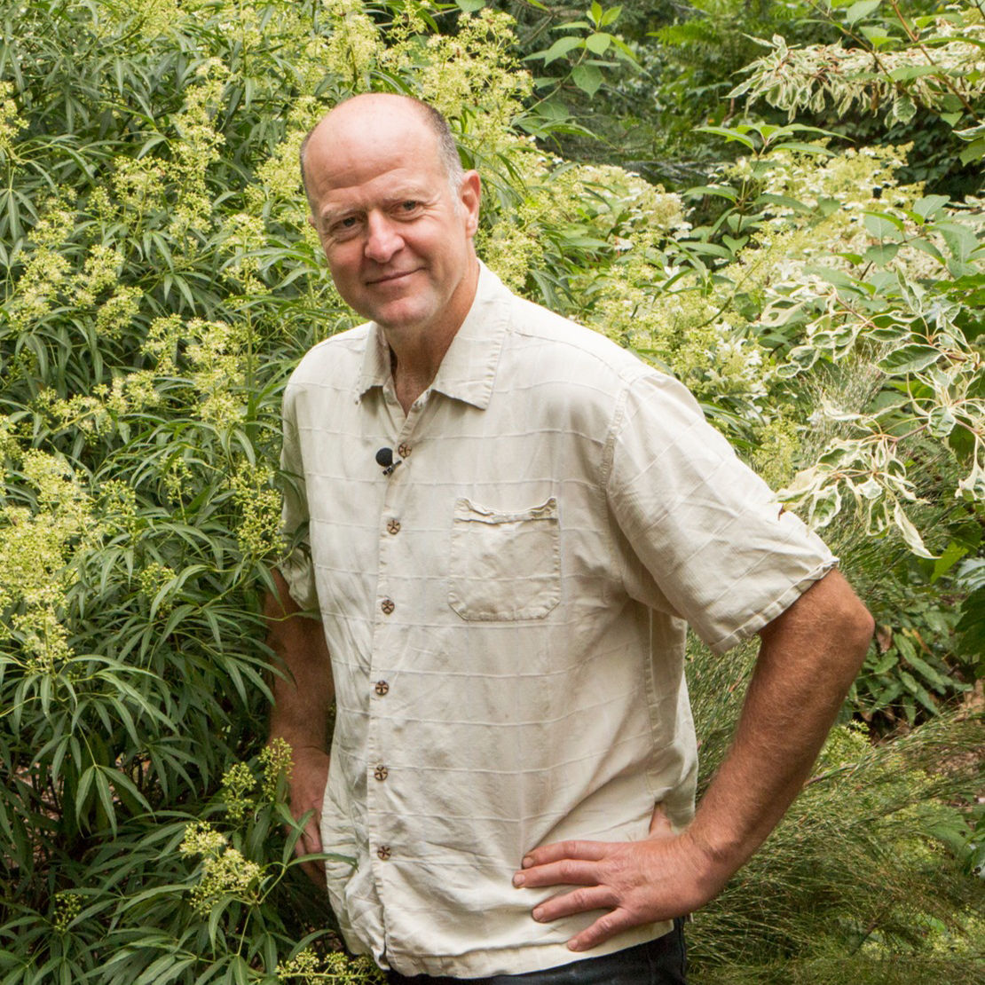 Dan Hinkley stands in front of a lush green background