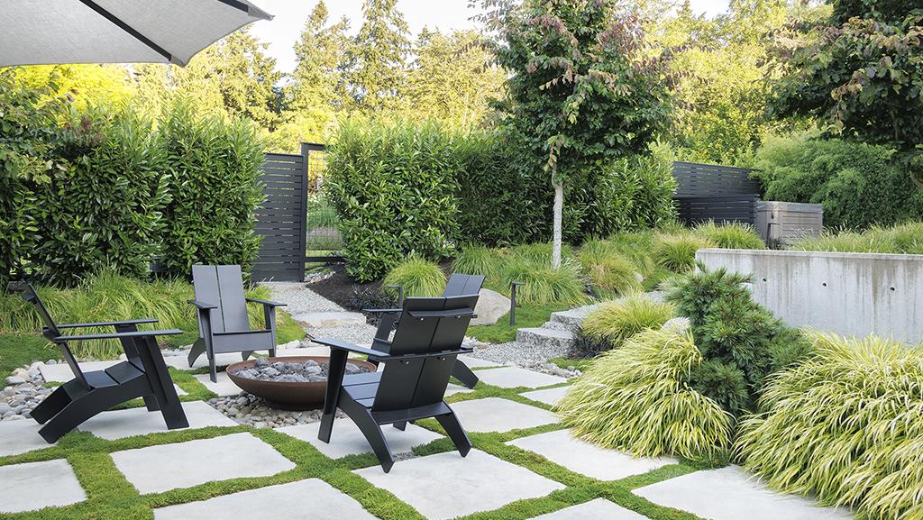 black chairs around fire bowl with green grassy landscaping