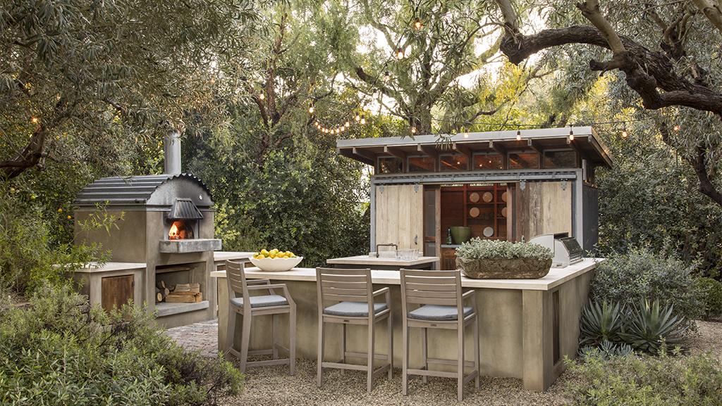 stylish outdoor living space with bar, fire stove, and out building