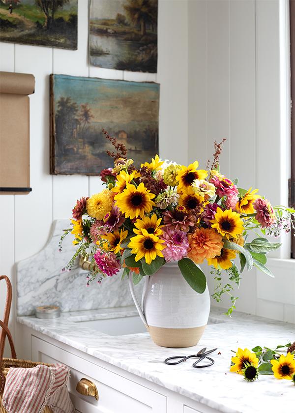 cut flower arrangement in white vase with sunflowers and zinnias