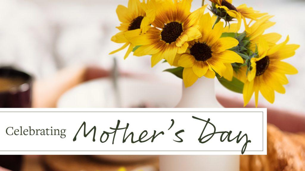 Bright, yellow sunflowers in white vase with text that reads, "Celebrating Mother's Day."