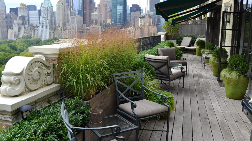 City patio landscape overlooking NY City filled with grasses, potted magnolia, oakleaf hydrangea and evergreens.