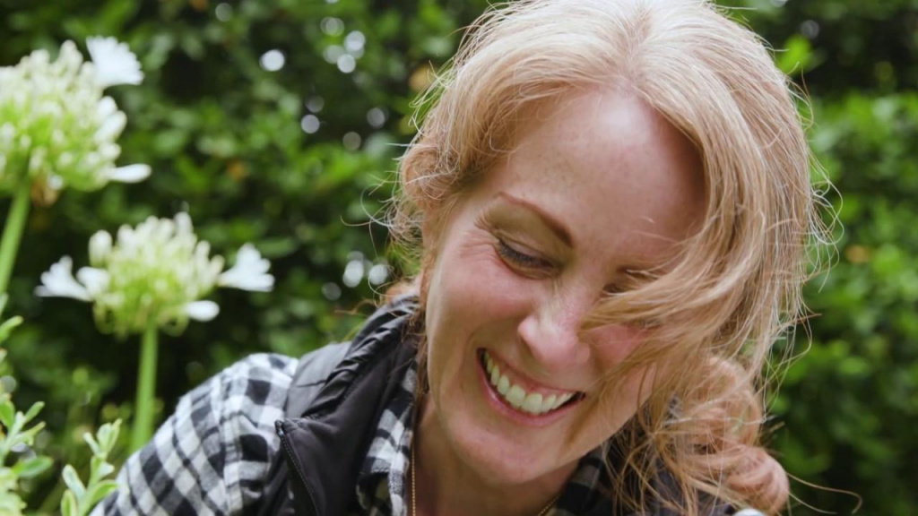 Headshot of writer Kelly Wilkniss smiling in a garden.