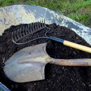 shovel and rake in a wheelbarrow of compost