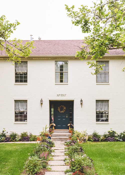 front of white house with sidewalk surrounded by low water cottage garden