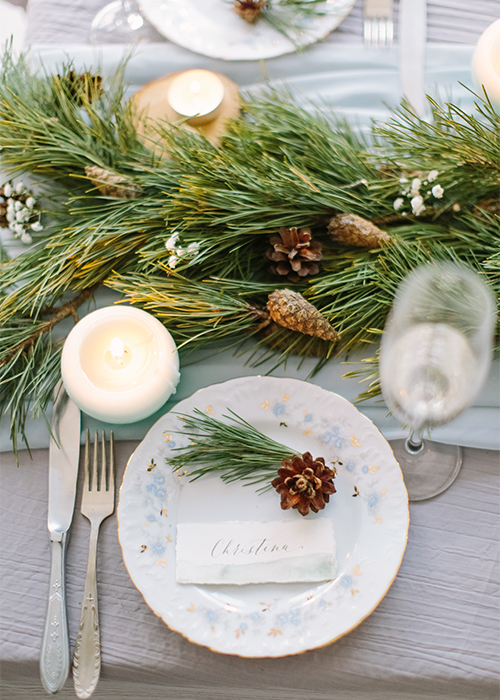 holiday table setting with conifer garland and pinecones