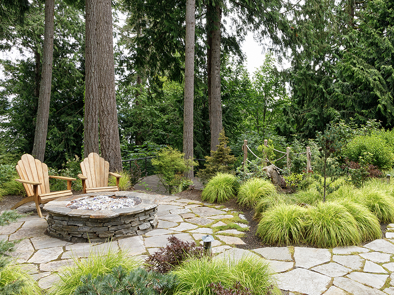 fire pit with adirondack chairs, stone pathway, and grass border