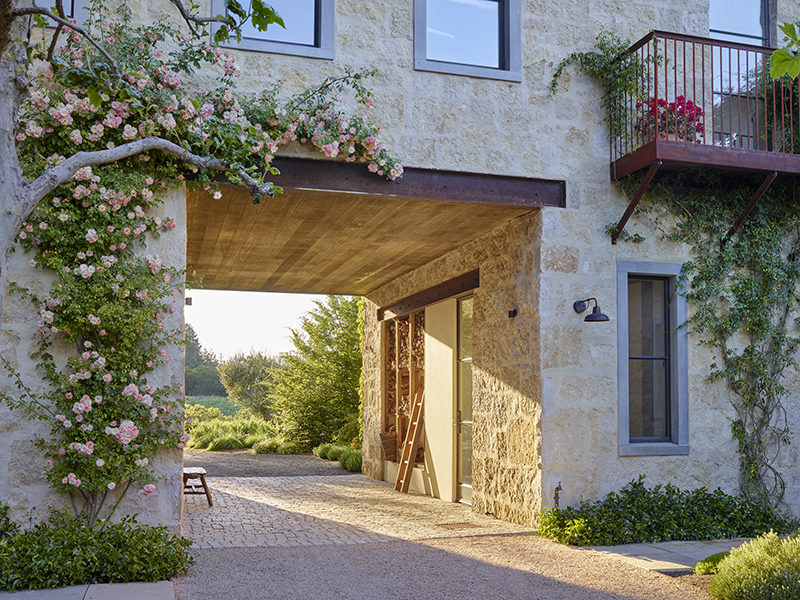 a stone breezeway with a climbing rose up the stone walls